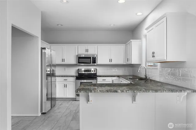 a kitchen with stainless steel appliances granite countertop a stove a sink and a refrigerator