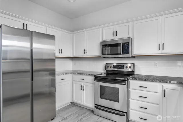 a kitchen with granite countertop white cabinets and stainless steel appliances