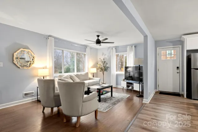 a living room with furniture a large window and wooden floor