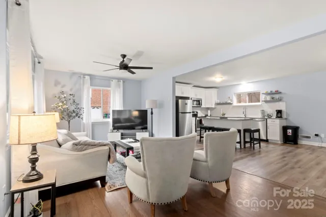 a living room with furniture kitchen view and a wooden floor