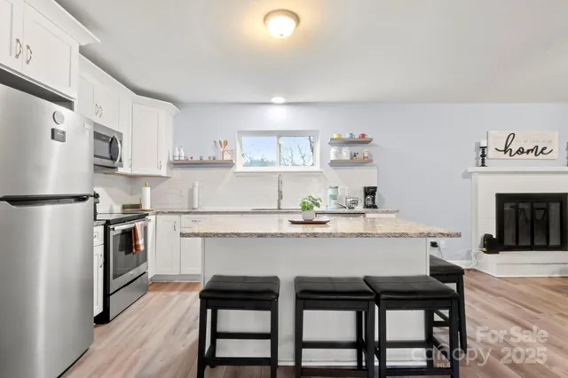 a kitchen with kitchen island a stove a table and chairs in it