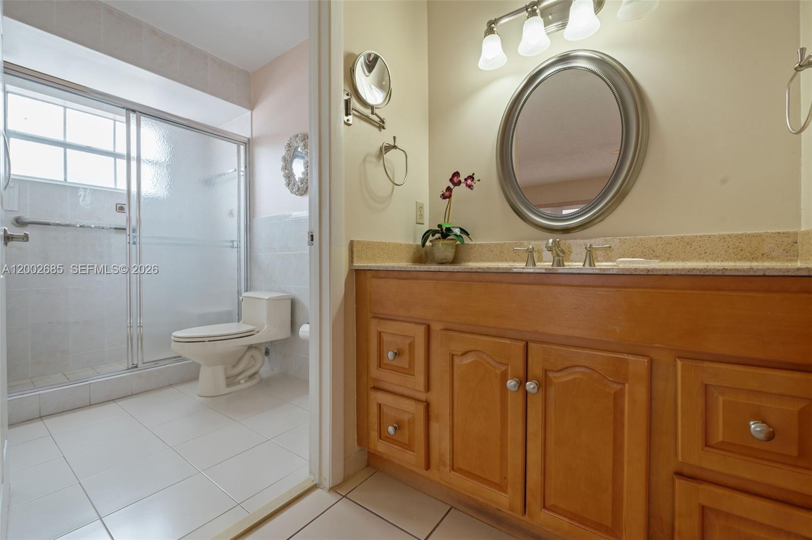 13440 Southwest 28th Street Miami, FL 33175 - Photo 16 of 35 a bathroom with a granite countertop toilet a sink and a mirror
