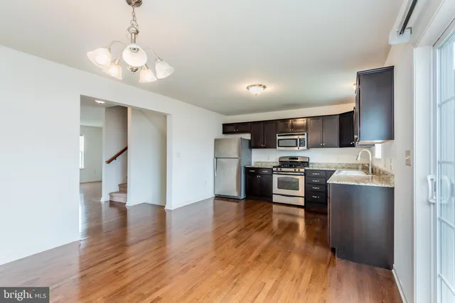 a kitchen with stainless steel appliances granite countertop a stove top oven a sink dishwasher and a refrigerator with wooden floor