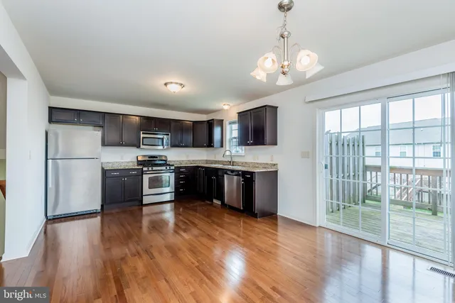 a kitchen with kitchen island granite countertop stainless steel appliances cabinets a sink and a large window