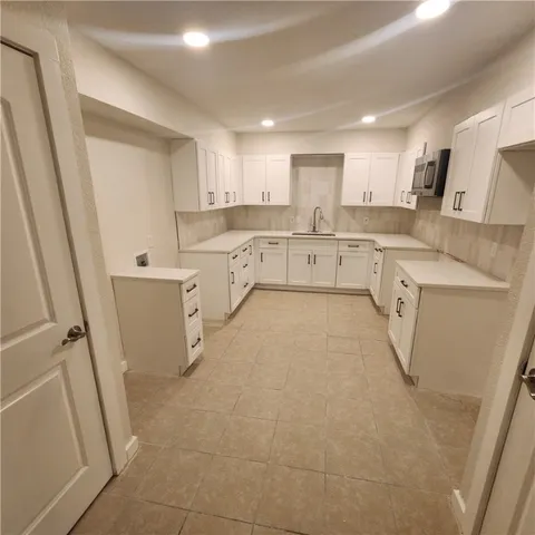 a large white kitchen with sink refrigerator and cabinets