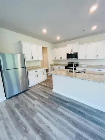 a kitchen with a refrigerator a stove top oven and white cabinets