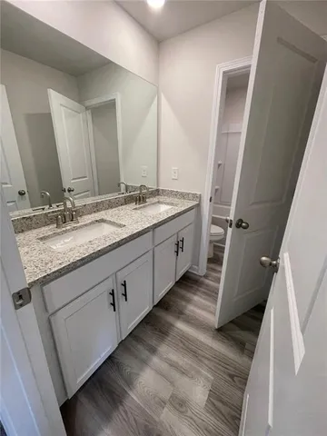 a bathroom with a granite countertop double vanity sink and mirror