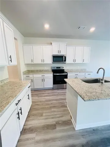 a large kitchen with stainless steel appliances granite countertop a sink stove and cabinets