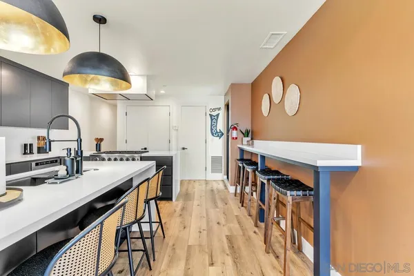 a kitchen with stainless steel appliances a stove a sink dishwasher and a dining table with wooden floor