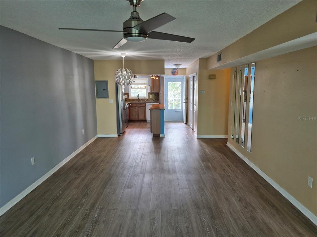 4939 Floramar Terrace, Unit 203 New Port Richey, FL 34652 - Photo 16 of 16 a view of a big room with wooden floor a ceiling fan and windows