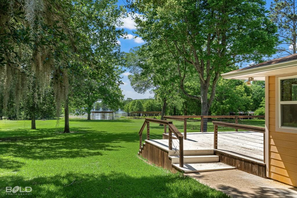225 Marie Road Ringgold, LA 71068 - Photo 3 of 40 Expansive green lawn with mature trees and a tranquil body of water in the background