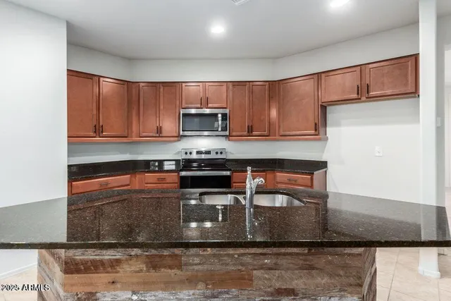 a kitchen with stainless steel appliances granite countertop a stove top oven a sink and a microwave