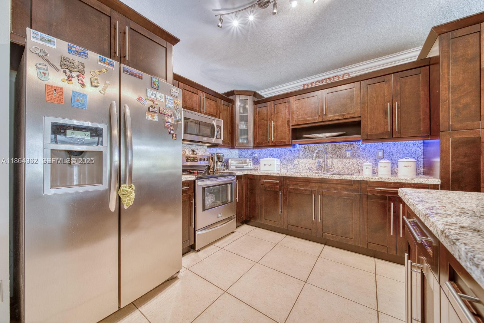 16886 Southwest 143rd Place Miami, FL 33177 - Photo 15 of 39 a kitchen with stainless steel appliances granite countertop a stove a sink and a refrigerator