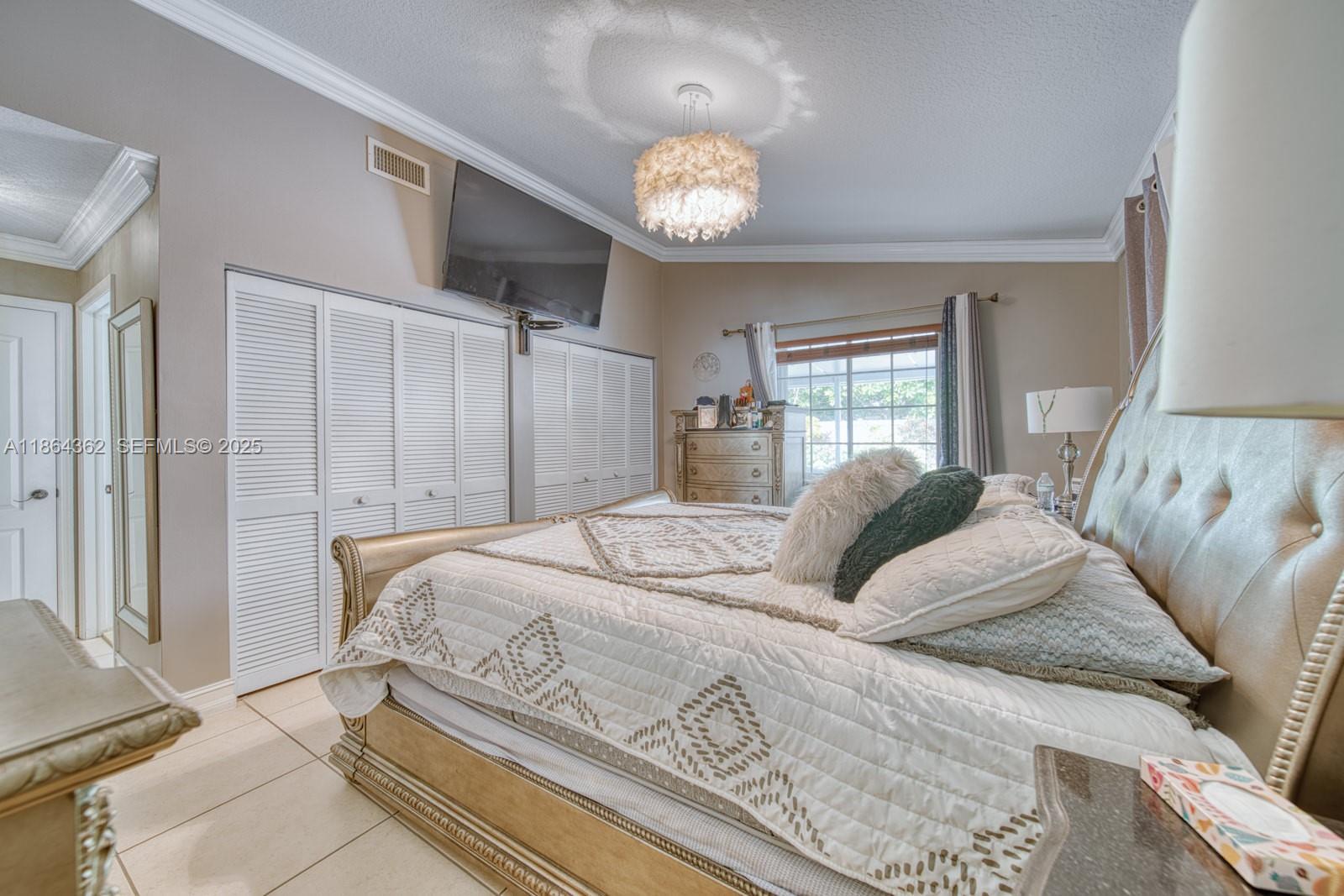16886 Southwest 143rd Place Miami, FL 33177 - Photo 21 of 39 a bedroom with a large bed and a chandelier