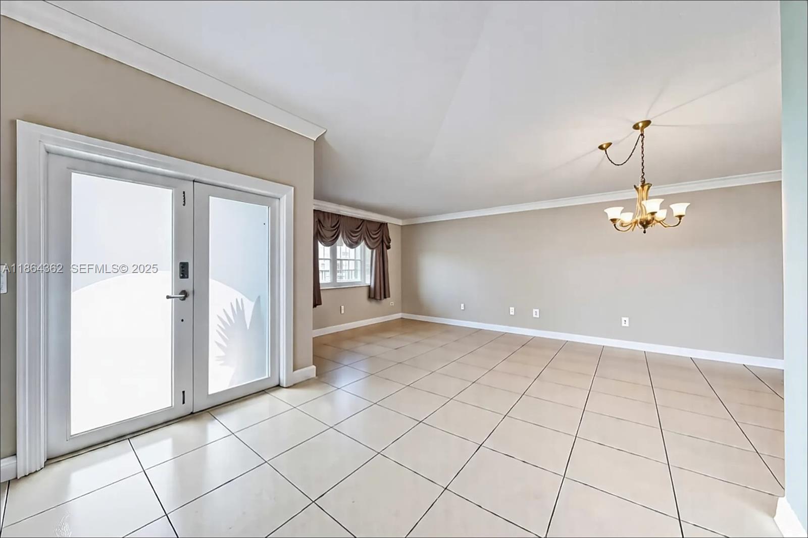 16886 Southwest 143rd Place Miami, FL 33177 - Photo 7 of 39 an empty room with chandelier and windows