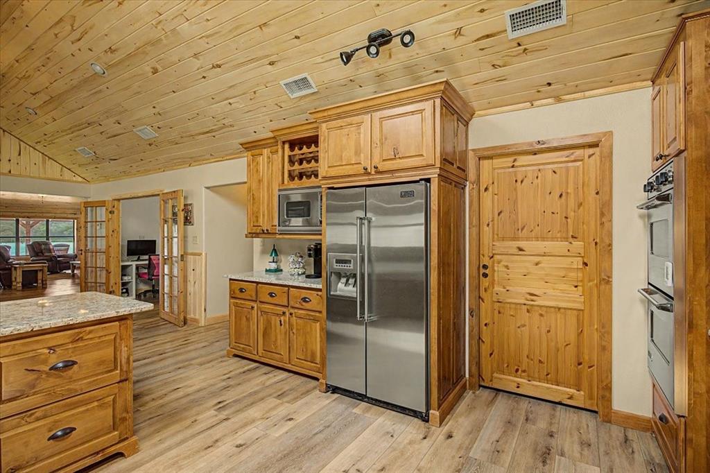 2789 Hanging Tree Road Bowie, TX 76230 - Photo 9 of 40 Kitchen with wood-finish flooring, wood cabinetry, granite countertops, and stainless steel appliances