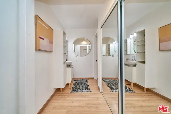 a view of a hallway with wooden floor and a bathroom