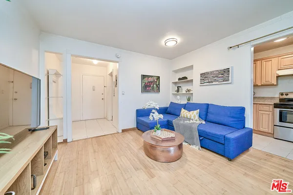 a living room with furniture a flat screen tv and kitchen view