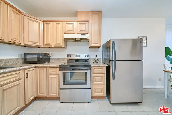 a kitchen with stainless steel appliances granite countertop a refrigerator sink and stove