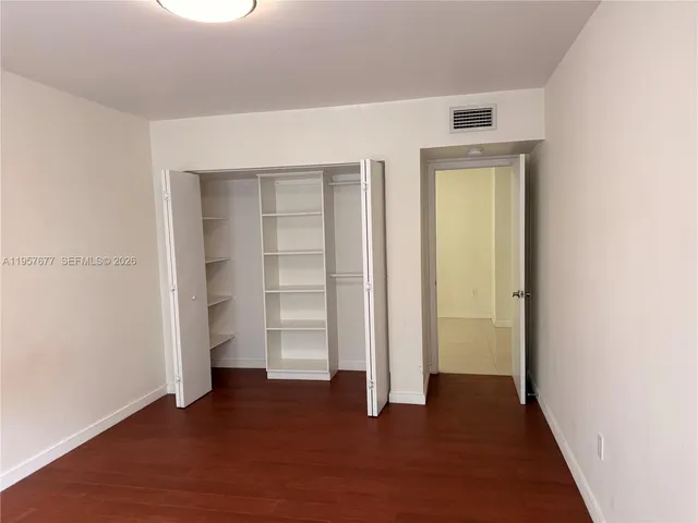 an empty room with closet and wooden floor