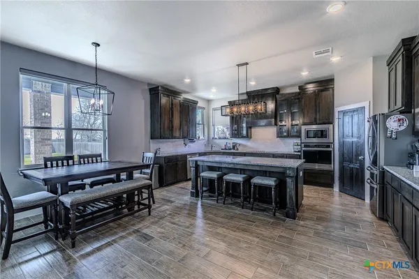 a kitchen with stainless steel appliances granite countertop a stove refrigerator and a fireplace