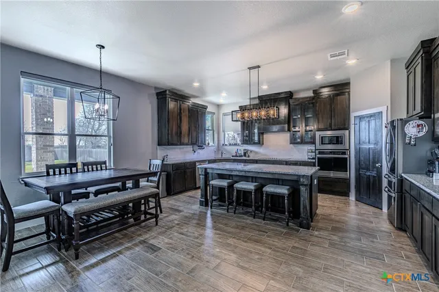 a kitchen with stainless steel appliances granite countertop a stove refrigerator and a fireplace