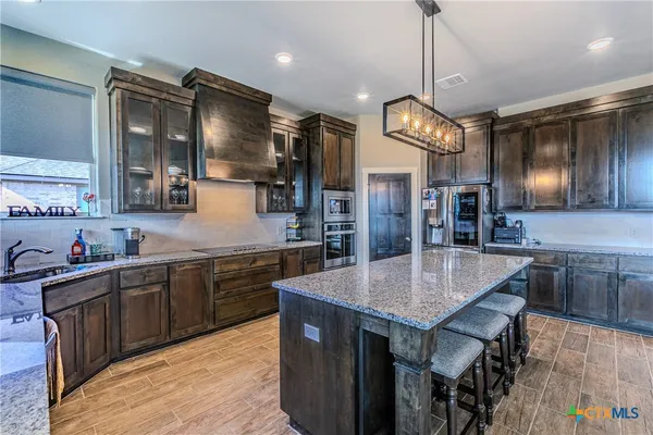 a kitchen with stainless steel appliances granite countertop a kitchen island a stove and a sink
