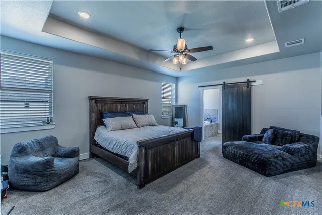 a spacious bedroom with a bed a couch and a chandelier