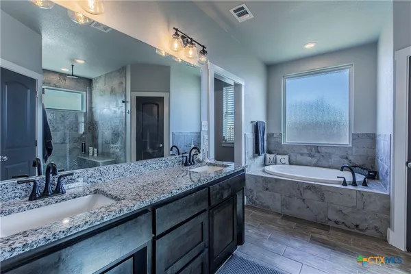 a bathroom with a granite countertop bathtub sink and mirror