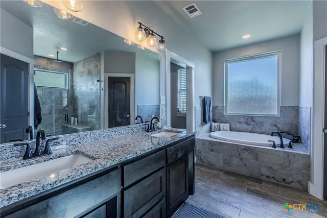 a bathroom with a granite countertop bathtub sink and mirror