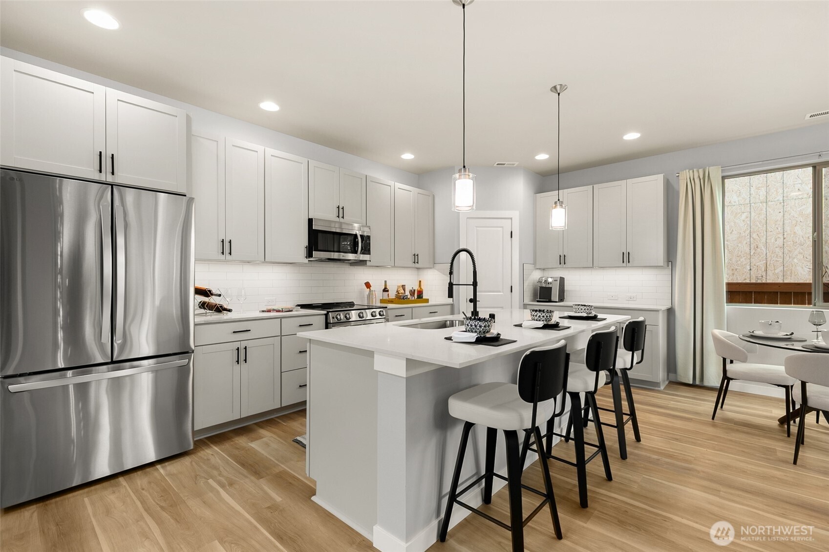 12506 Southeast 256th Place, Unit 8 Kent, WA 98030 - Photo 8 of 26 a kitchen with stainless steel appliances a stove a sink a refrigerator a center island a dining table and chairs