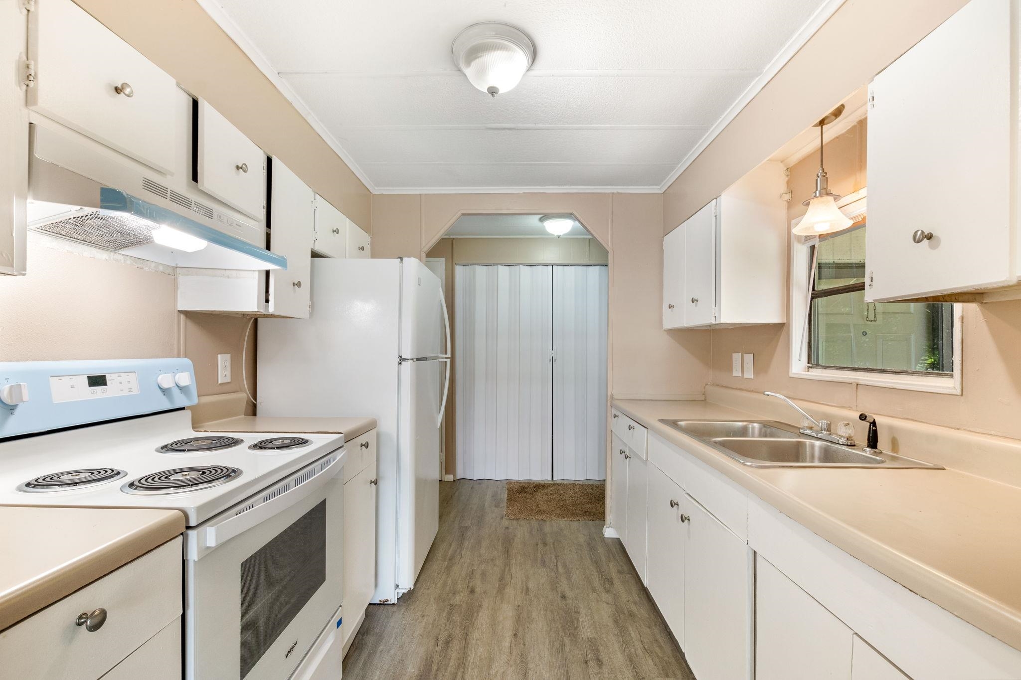 4541 Fourth Avenue St. Augustine, FL 32095 - Photo 15 of 32 a kitchen with stainless steel appliances a sink dishwasher stove refrigerator and white cabinets with wooden floor
