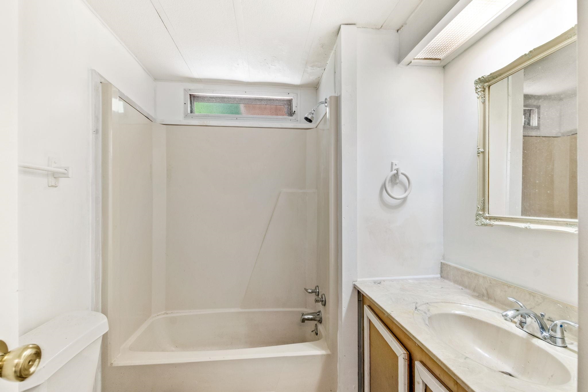 4541 Fourth Avenue St. Augustine, FL 32095 - Photo 26 of 32 a bathroom with a granite countertop sink a mirror and a bathtub