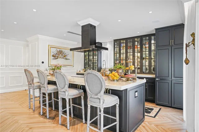 a room with stainless steel appliances kitchen island granite countertop a table chairs and a wooden floor