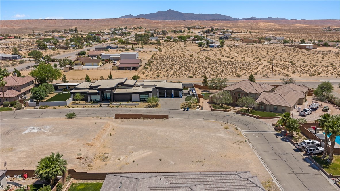 1141 Thomas Bay Circle Logandale, NV 89021 - Photo 9 of 16 An aerial view reveals an expansive desert landscape with residential properties and distant mountains under a clear sky.