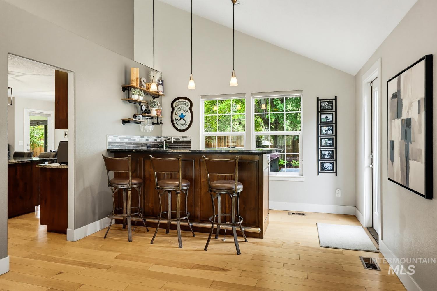 369 South Winthrop Way Boise, ID 83709 - Photo 8 of 50 Vaulted ceilings accent a custom bar area featuring a dark wood base and a dark countertop
