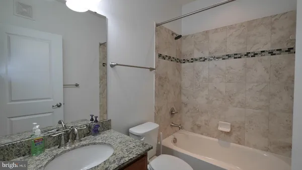 a bathroom with a granite countertop sink mirror toilet and bathtub