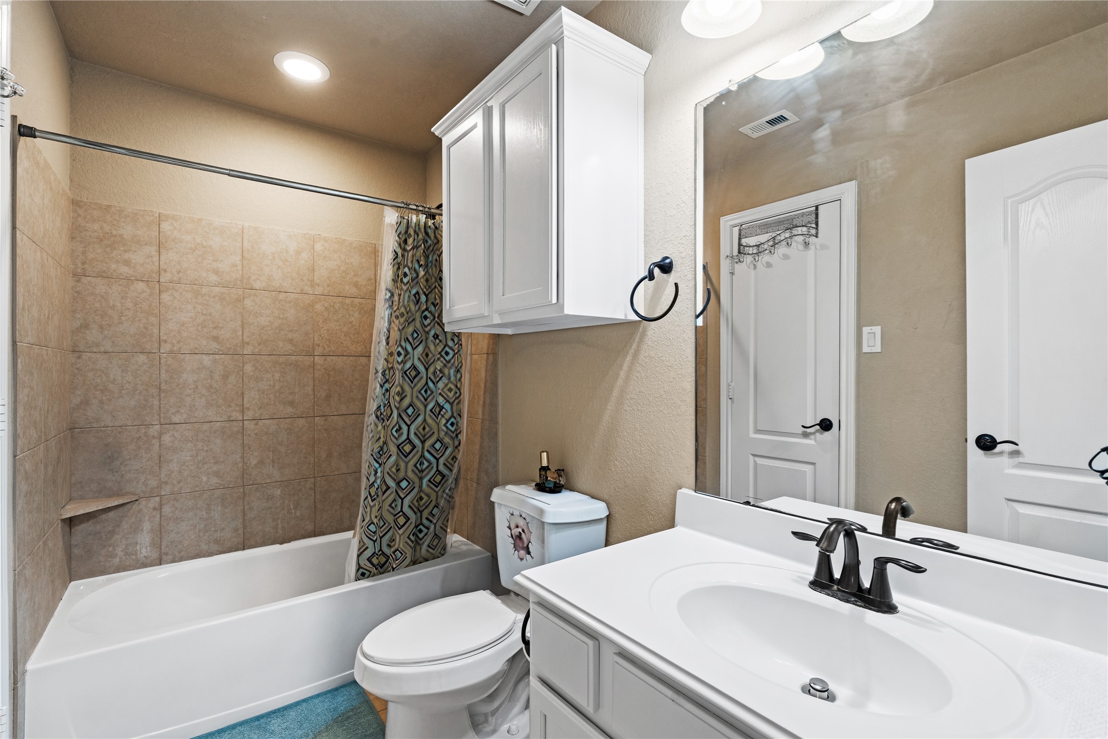 5802 Layton Meadows Lane Spring, TX 77379 - Photo 31 of 42 Full bathroom with tub. White vanity, tiled tub/shower, white overhead cabinet, matching hardware.
