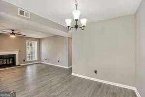 an empty room with a chandelier fan and wooden floor