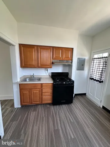 a kitchen with granite countertop wooden cabinets a stove and a wooden floor