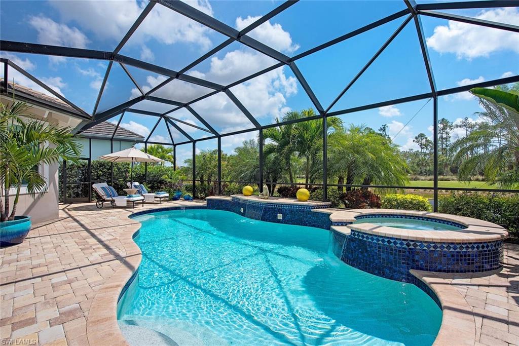 5098 Andros Drive Naples, FL 34113 - Photo 7 of 22 a view of a swimming pool with a table and chairs under an umbrella