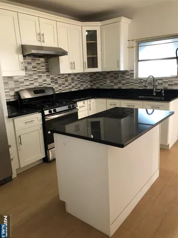 a kitchen with granite countertop a sink a stove and cabinets