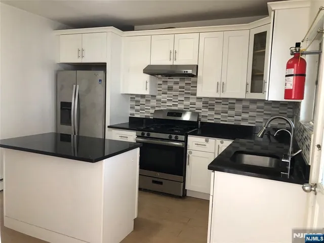 a kitchen with granite countertop a refrigerator stove and sink