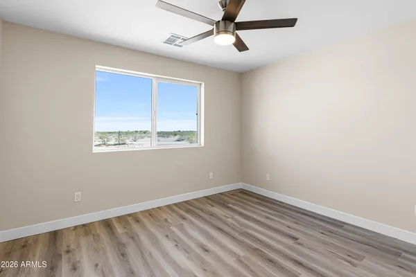 a view of empty room with wooden floor and fan