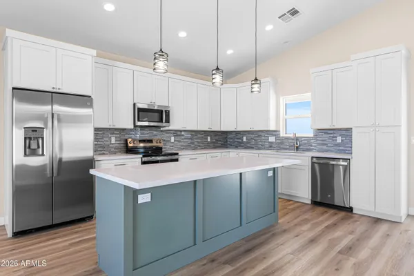 a kitchen with a refrigerator a microwave a sink and wooden floor