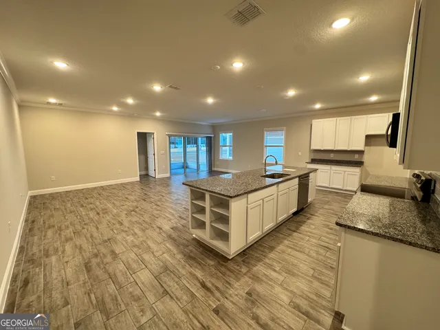 a large kitchen with stainless steel appliances a large counter top a stove a sink and a refrigerator