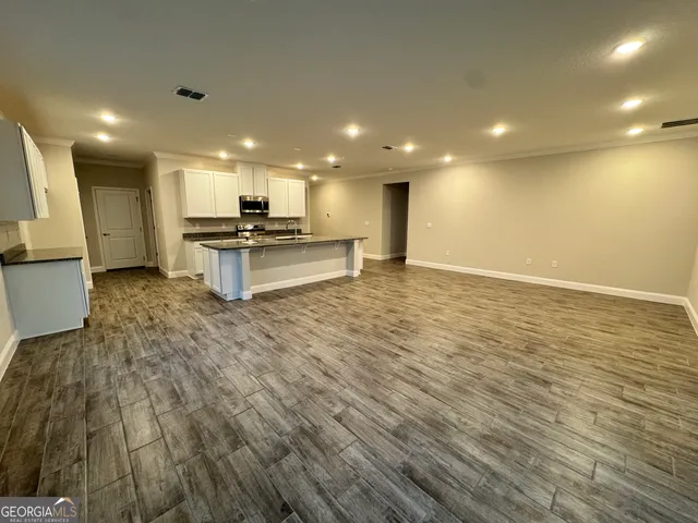 a view of a kitchen with kitchen island a sink wooden floor and a counter top space