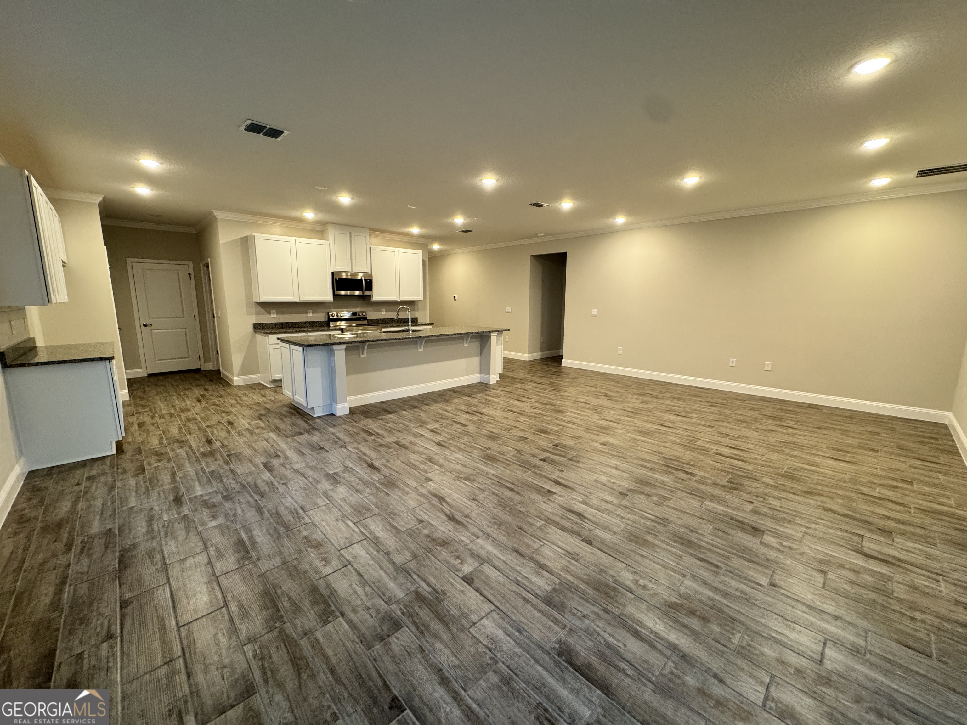 108 Brookshire Grn Court Kingsland, GA 31548 - Photo 7 of 21 a view of a kitchen with kitchen island a sink wooden floor and a counter top space