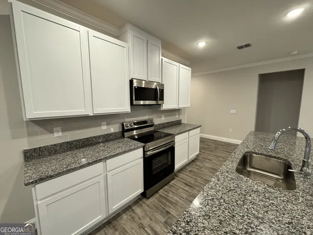 a kitchen with granite countertop a sink stove and cabinets