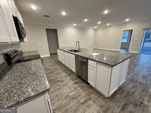 a kitchen with stainless steel appliances granite countertop a sink stove and refrigerator